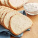 Sliced bread on a table next to a bowl of flour.