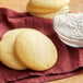 A stack of cookies on a red cloth with a bowl of White Lily Enriched Bleached All-Purpose Flour.