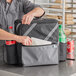 A man in a chef's uniform putting food in a Choice insulated cooler backpack.