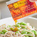 A person pouring a Lee Kum Kee Chiu Chow Style Chili Oil packet into a bowl of food.