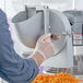 A person using a Shredder and Slicer Attachment to cut carrots.