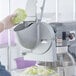 A person using a Shredder and Slicer Attachment to slice lettuce in a machine.