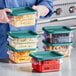 A woman holding a Vigor square polycarbonate food storage container with shredded cheese in it.