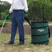 A man wearing blue pants and black gloves using a green and black Unger Nifty Nabber to pick up garbage.