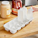 A hand holding a white plastic container with bottles of liquid in it.