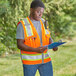 A man in an Ergodyne orange reflective safety vest holding a clipboard.