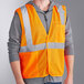 A man wearing an Ergodyne orange reflective mesh vest over a grey jacket.