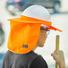 A man wearing an orange Ergodyne hard hat with a brim and neck shade.