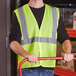 A man wearing an Ergodyne lime safety vest holding a red handle.