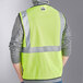 A man wearing a lime yellow Ergodyne high visibility mesh vest.