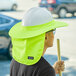 A person wearing a lime green Ergodyne hard hat with a neck shade.