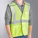 A man wearing an Ergodyne lime yellow safety vest over a grey shirt.