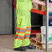 A man wearing Ergodyne lime and reflective safety pants over a white background.
