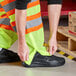 A person wearing Ergodyne GloWear high visibility pants over black shoes.