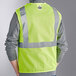 A person wearing a lime Ergodyne high visibility mesh vest with reflective stripes.