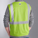A person wearing an Ergodyne lime green mesh safety vest with reflective stripes.
