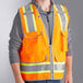 A man wearing an Ergodyne orange reflective surveyor vest over a grey shirt.