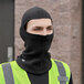 A man wearing a black balaclava and yellow reflective vest.