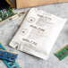 A white Multisorb silica packet with black text next to computer chips and a blue circuit board.