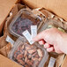 A hand holding a Multisorb StripPax desiccant packet over a box of food.