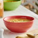 An Acopa Capri coral stoneware bowl filled with soup on a table.