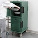 A man standing next to a granite green Cambro food pan carrier.