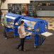 Two women holding trays of food next to a navy blue Cambro Versa Salad Bar on heavy-duty casters.