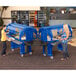 Two women using a navy blue Cambro Versa food cart to serve themselves in an outdoor catering setup.