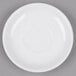 A Tuxton white china saucer with a small rim on a gray surface.