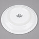 A Tuxton white china cappuccino saucer with black text on it.