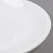 A close-up of a white Tuxton China saucer with a rim.