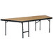 A rectangular table with black legs and a hardboard surface on a National Public Seating portable stage pie unit.