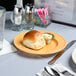 A Tuxton plate with food and a glass of water on a table.