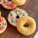 Schar gluten-free plain bagels with cream cheese and onions on a cutting board.