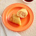 An Acopa Valencia orange stoneware plate with food on it.