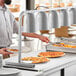 A man using a ServIt pass through heat lamp to serve food at a buffet.
