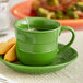 An Acopa Capri Palm Green stoneware cup with a tea bag on a plate.