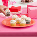 A person holding a cupcake on a Rio Orange oval melamine platter.