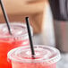 A close-up of a Choice black unwrapped straw in a plastic cup.