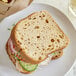 A sandwich made with Schar Multigrain Bread on a white plate.