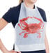 A woman wearing a white disposable bib with a red crab on it.