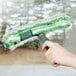 A hand holding a green and white Unger Monsoon Plus StripWasher Sleeve cleaning a window.