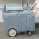 A person pushing a Cambro Mobile Ice Bin with a sliding lid.