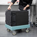 A man using a Cambro Camdolly to move a black Cambro box.