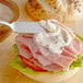 A sandwich with ham and cheese on a plate with a white rectangular bowl of AAK Select Recipe salad dressing on the side.