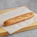 A long loaf of Schar gluten-free baguette on a wooden cutting board.