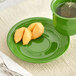 A green Acopa Capri stoneware saucer with fortune cookies and a cup of tea.