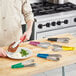 A man using Choice stainless steel scalloped tongs to put food on a plate.