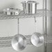 A metal shelf with a Choice aluminum cookware set on it.