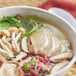 A bowl of Lee Kum Kee mushroom bouillon soup with mushrooms and greens.